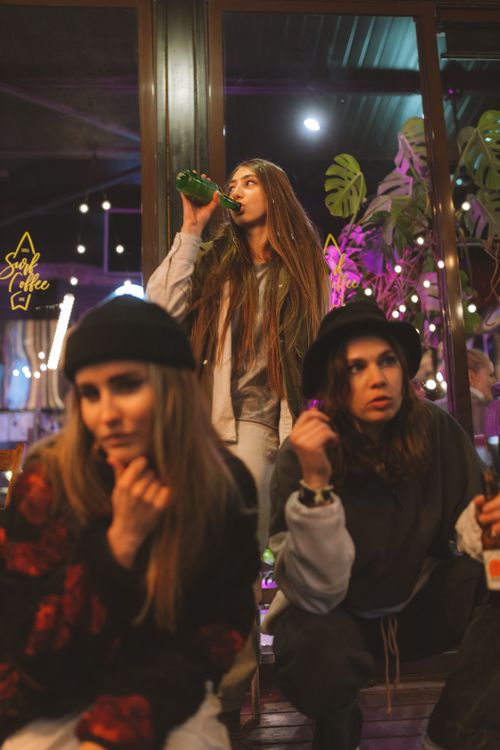 Free Three young women having a fun night out at a cozy indoor cafe with drinks. Stock Photo