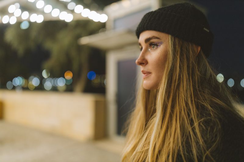 Woman wearing a black beanie at night with bokeh lights