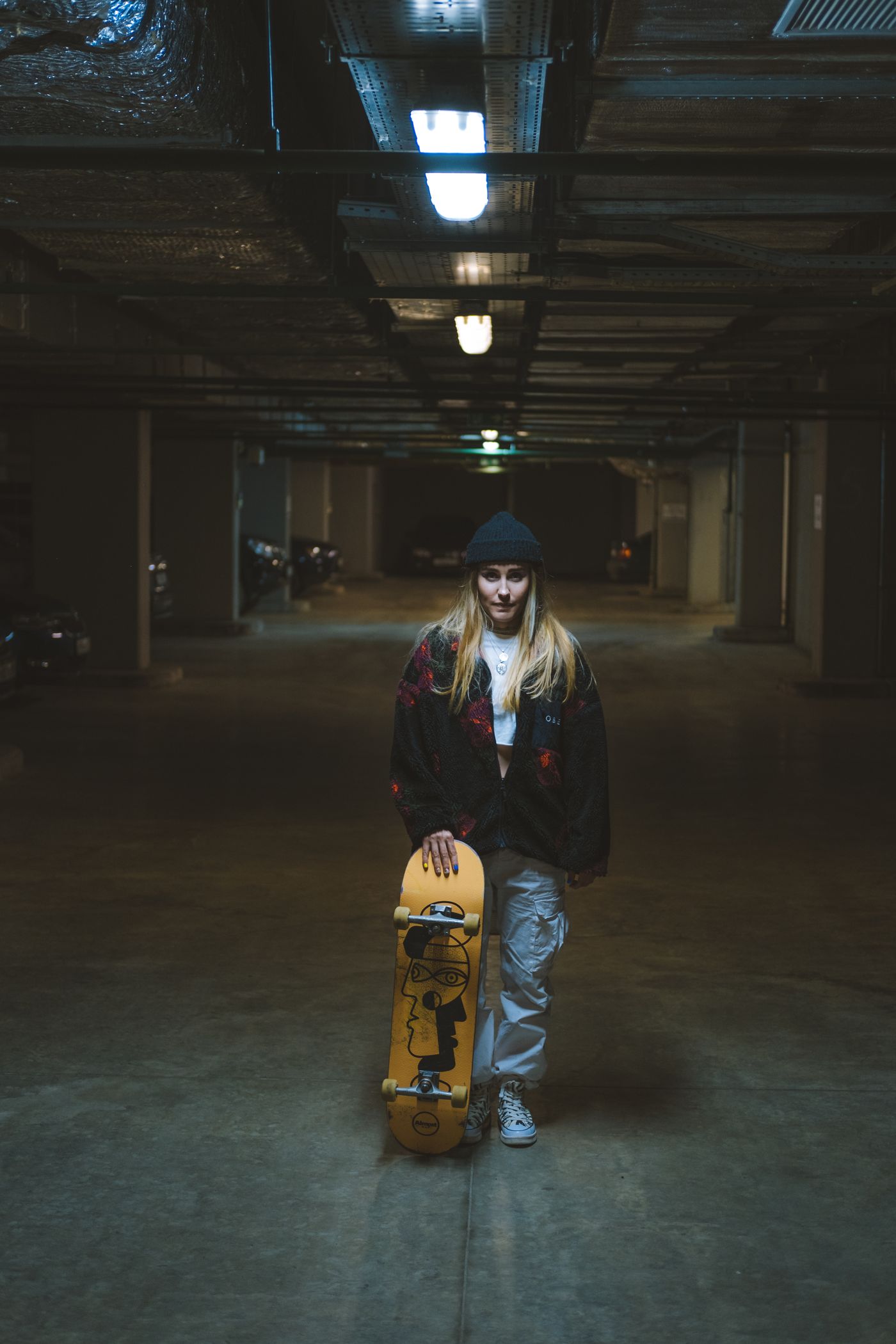 Skateboarder wearing a black beanie in a dimly lit underground car park