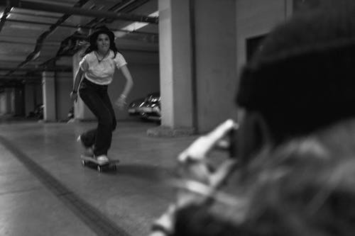 Grayscale Photo of a Woman Riding a Skateboard