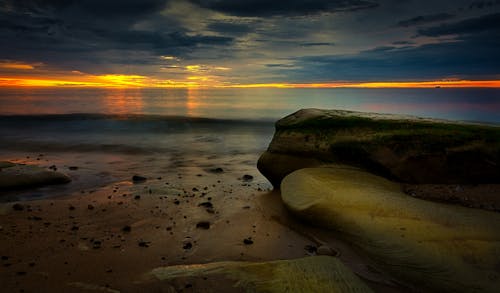 Brown Rock Formation on Seashore during Sunset