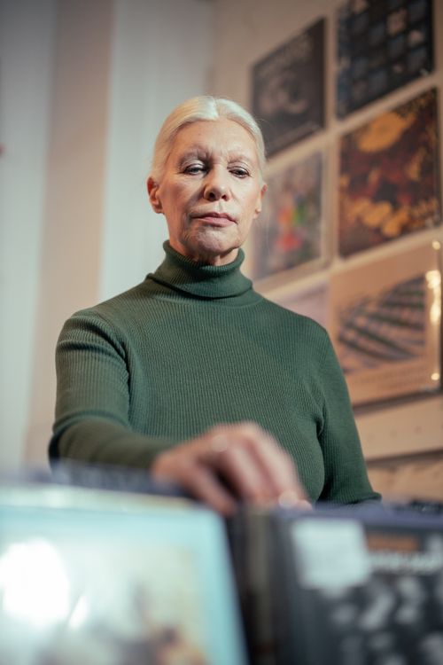 Free Elderly woman looking through vinyl records in a music shop. Stock Photo