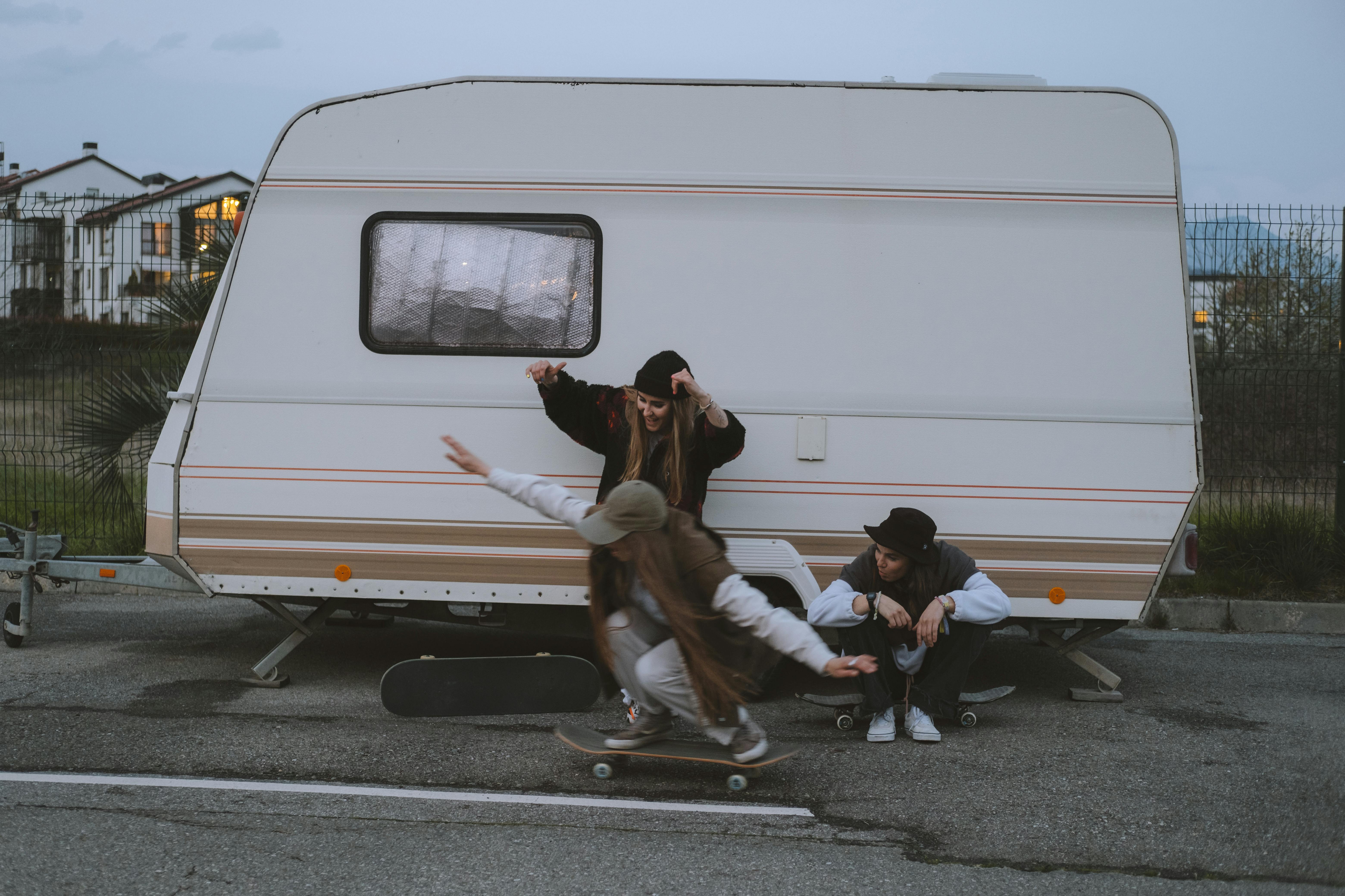 girls with skateboards near van on parking lot