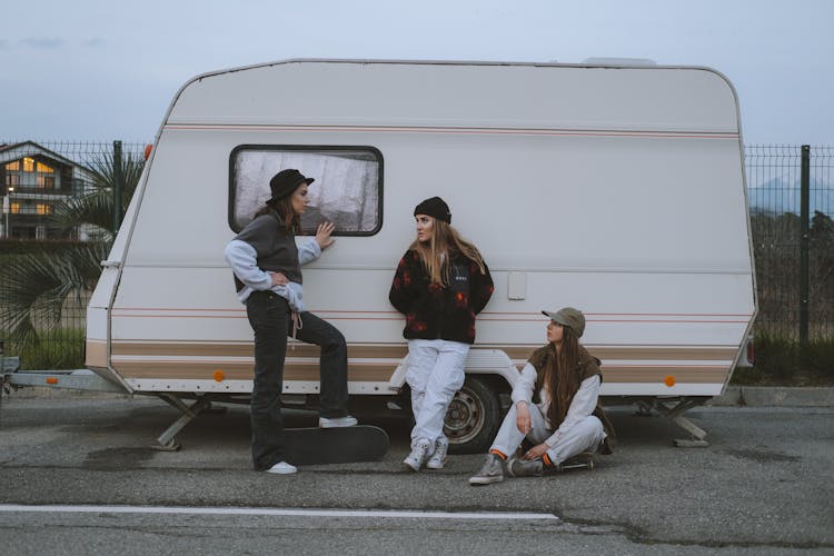 Girls With Skateboards Hanging Out Beside A Mini Camper 