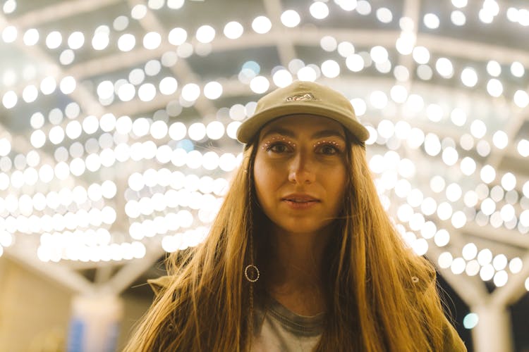 Portrait Of A Young Woman In A Cap Near Bright Lights