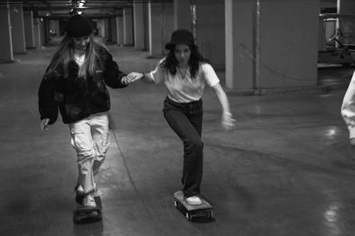 Grayscale Photo of Women Riding Skateboard