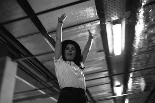 Grayscale Photo of a Woman Raising Her Arms