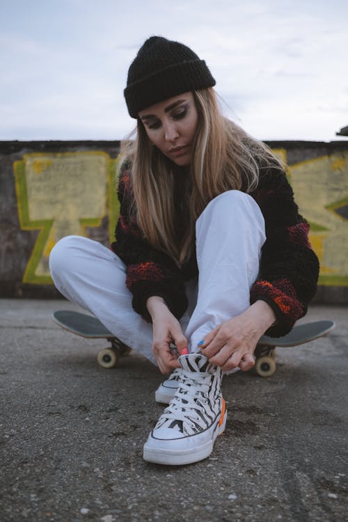 Free Woman in Beanie Hat Sitting on Skateboard  Stock Photo