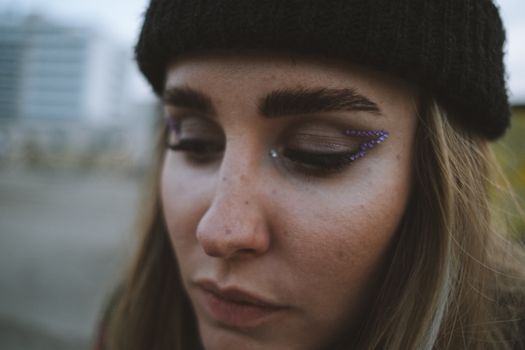 A close-up of a woman with artistic glitter eye makeup, showcasing a modern beauty style.