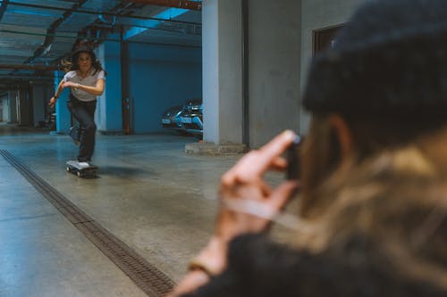 A Person Taking a Photo of a Skateboarder in a Parking Lot