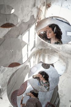 Ethnic female reflecting in mirrored surface on building while standing on sidewalk on street with friend with smartphone in city