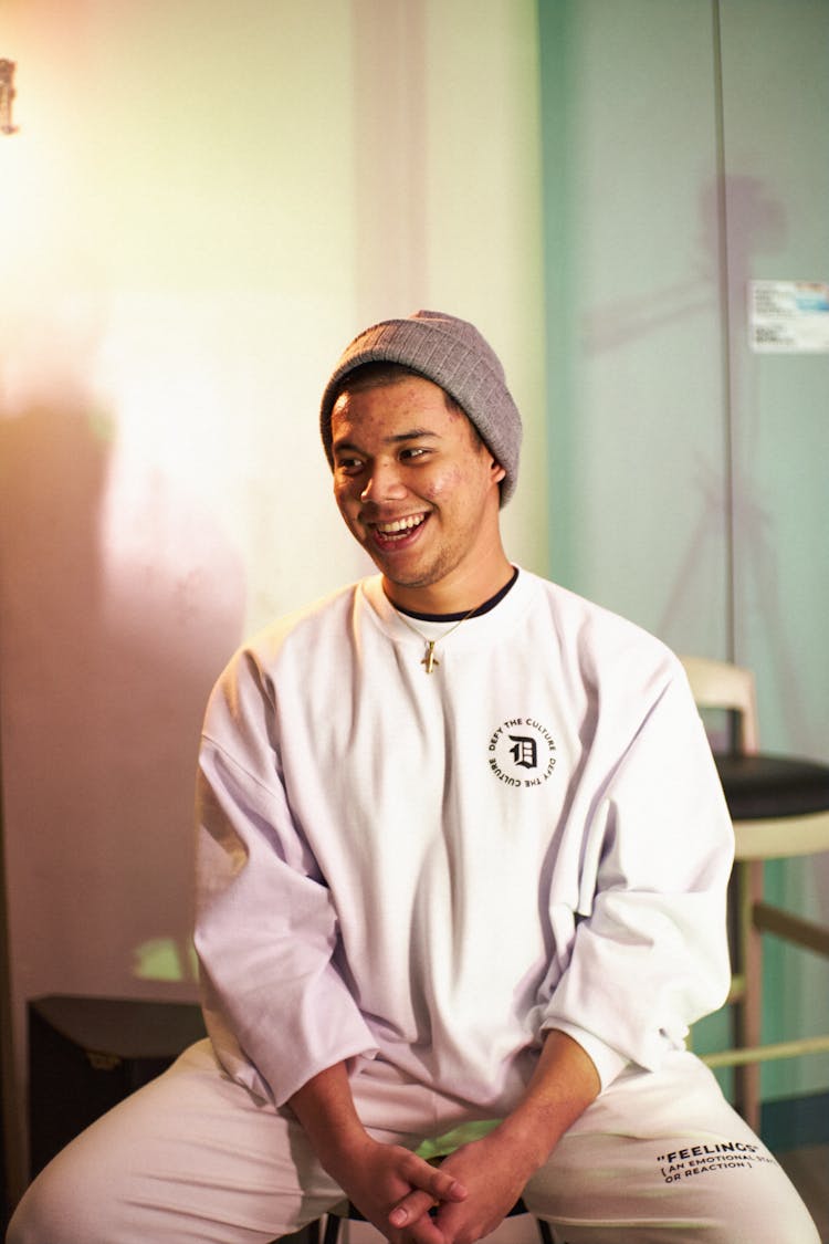 Man In White Sweatsuit Sitting On Stool