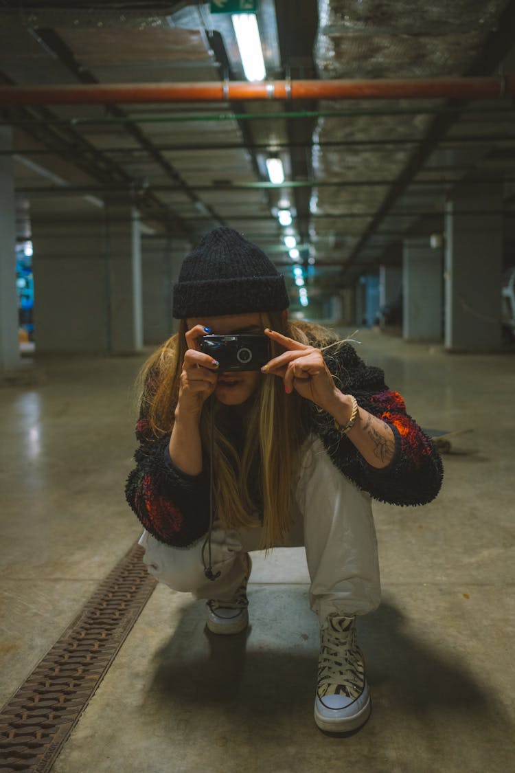 A Woman Crouching On The Concrete Floor Taking A Photo