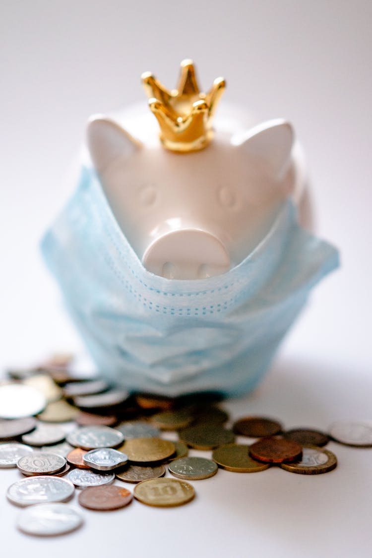 Piggy Bank In Protective Mask And Crown With Coins