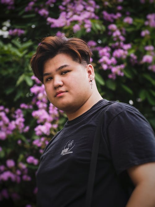 Man in Black Crew Neck T-shirt Standing Near Purple Flowers