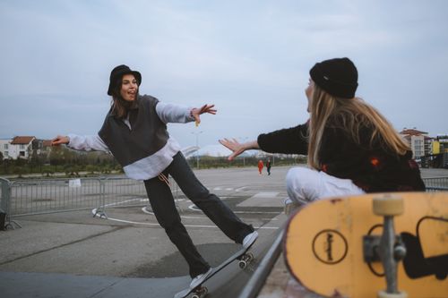 Free Two women enjoying an outdoor skateboarding session in an urban area, exuding energy and friendship. Stock Photo
