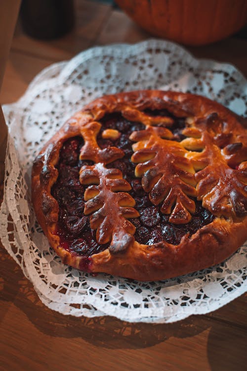 From above of sweet delicious baked pie with berry filling served on white napkin on wooden table in light room