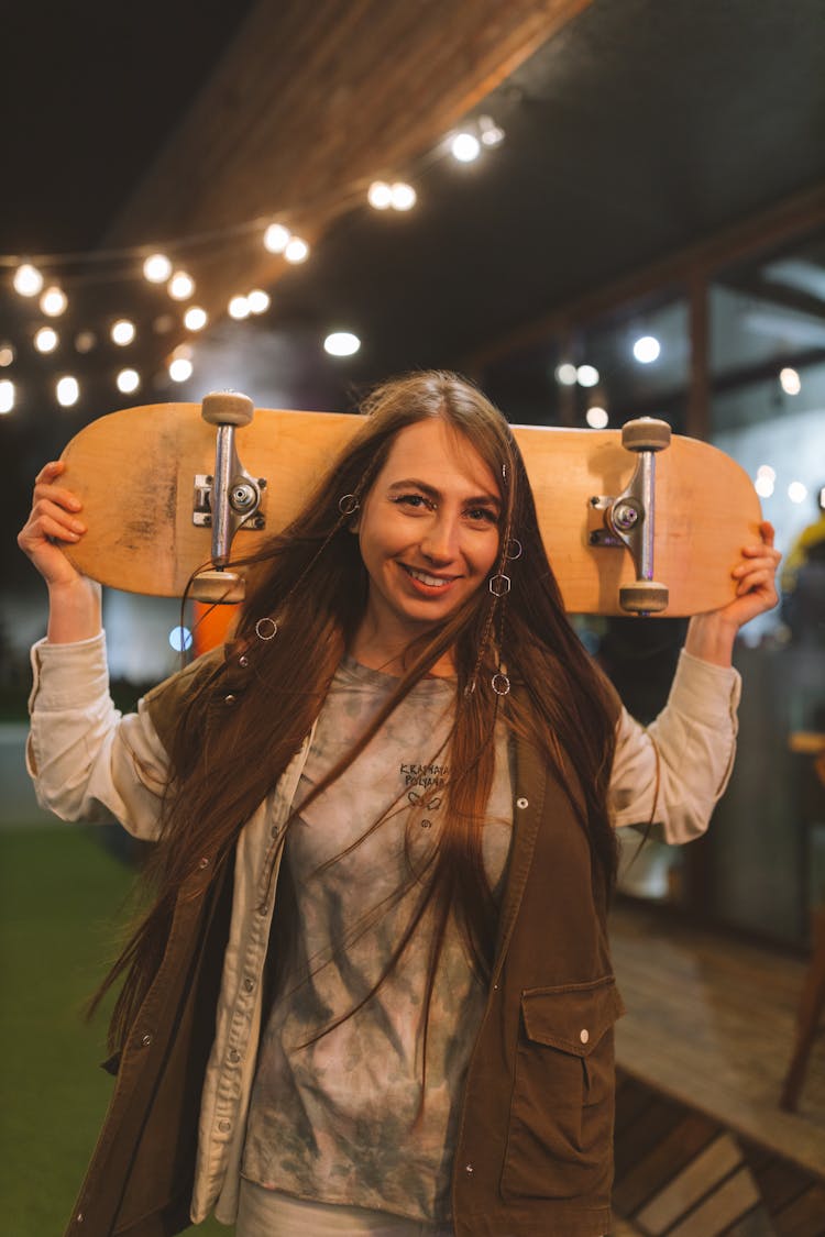 A Woman Holding Brown Skateboard