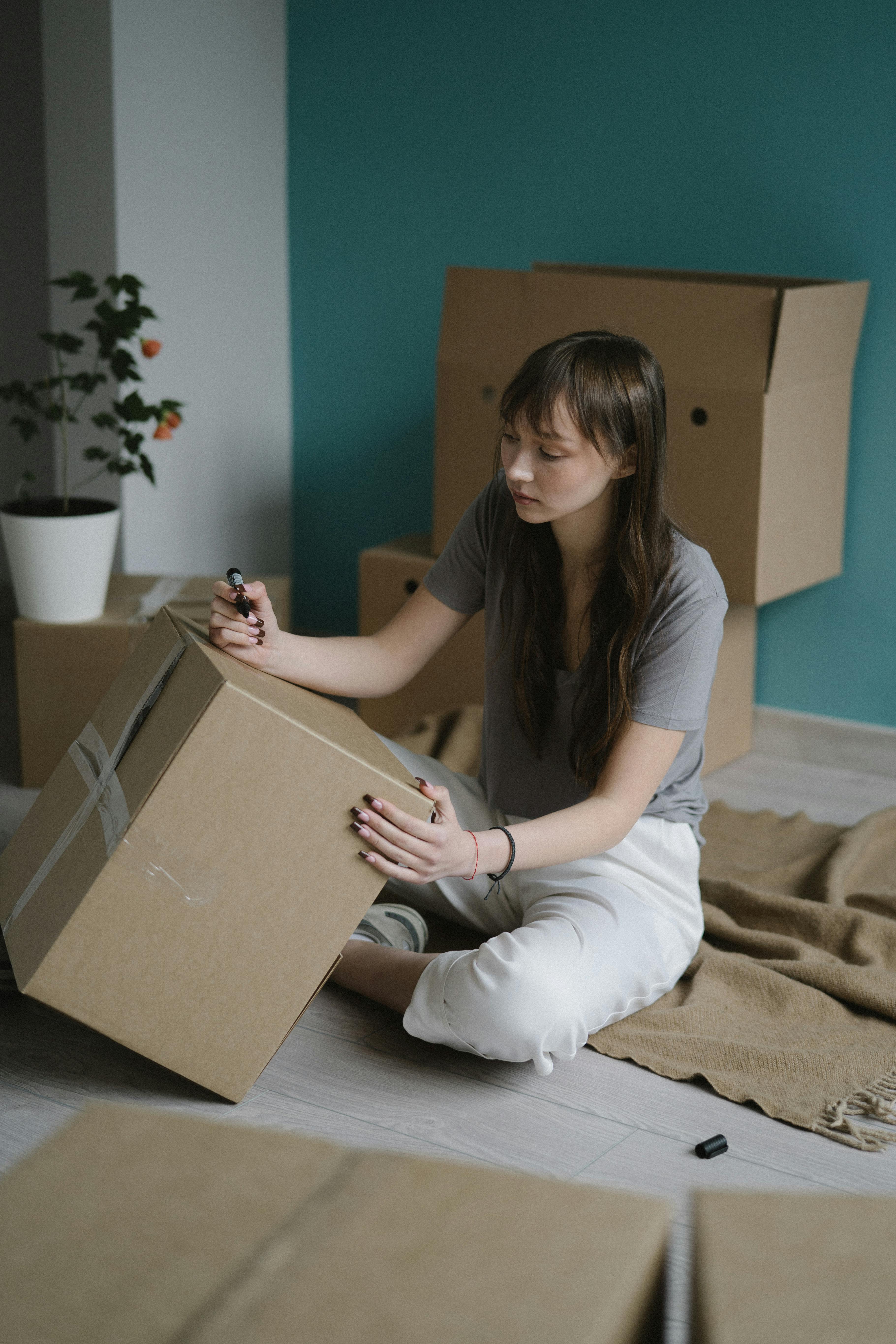 a woman labeling boxes with a pen marker