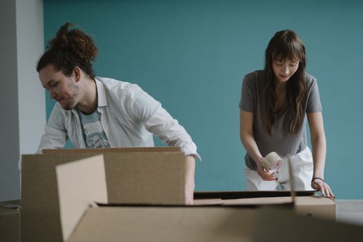 A couple packing boxes together, preparing for a move into their new home.