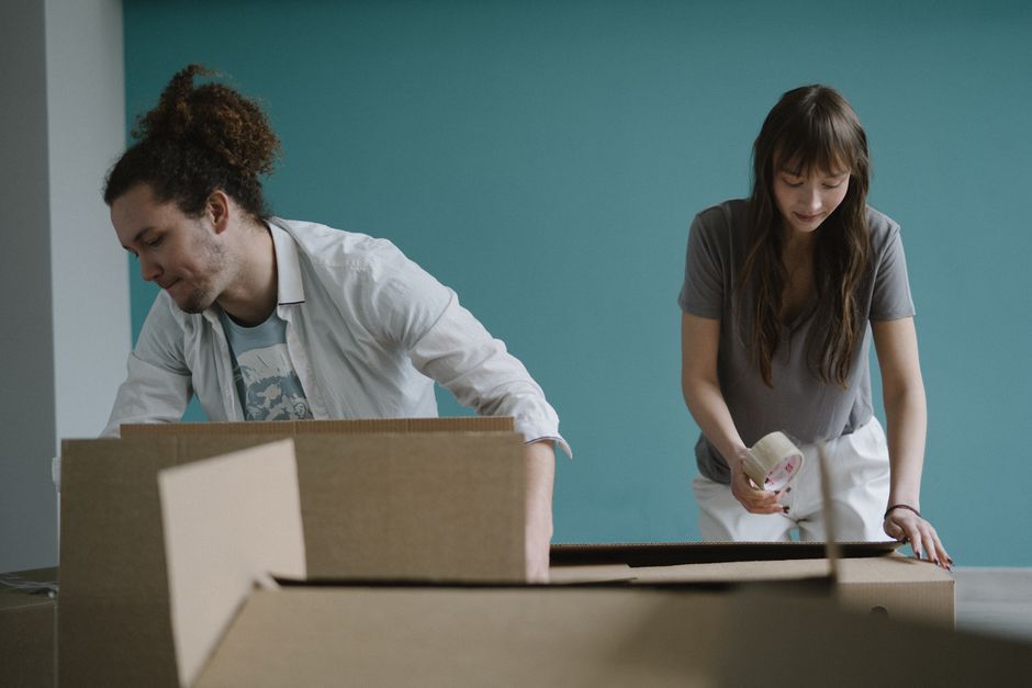 Una pareja empaquetando cajas juntos, preparándose para mudarse a su nuevo hogar.