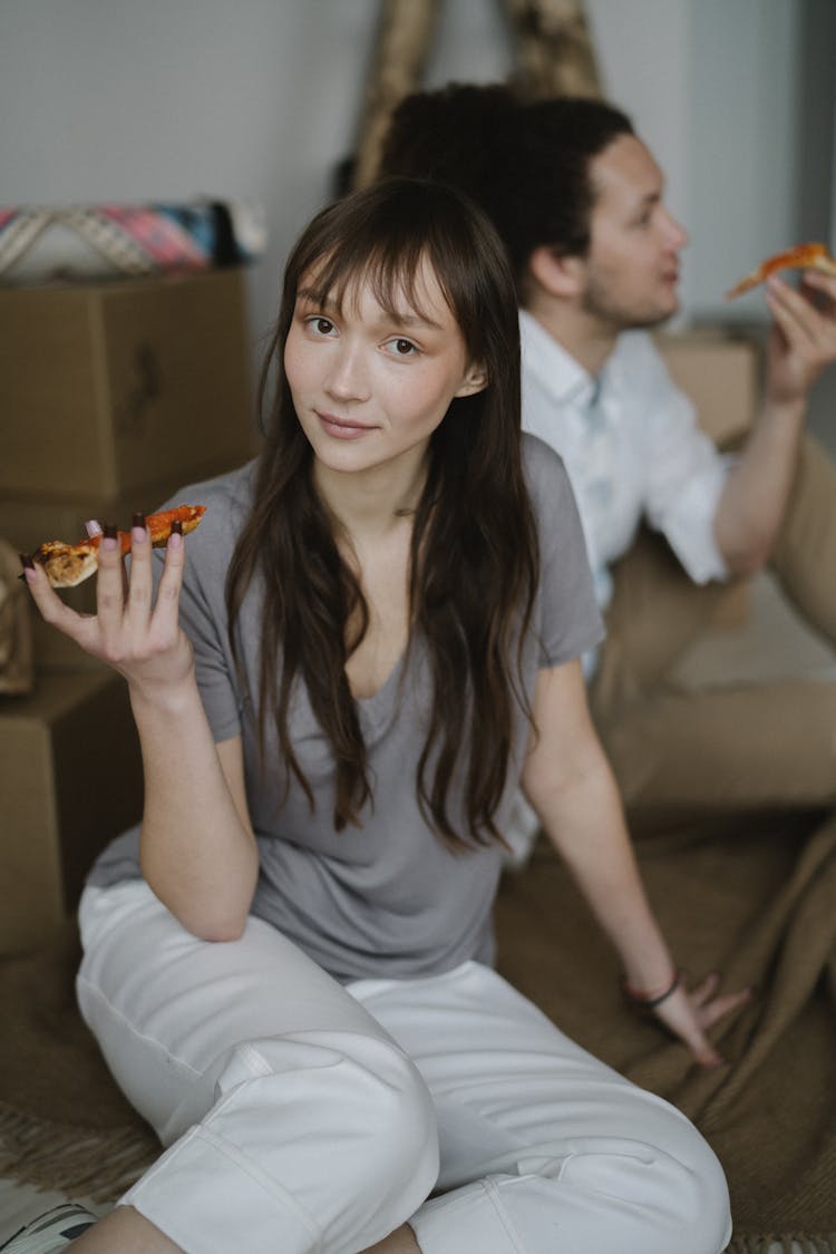 A Woman In Gray Shirt Holding A Pizza