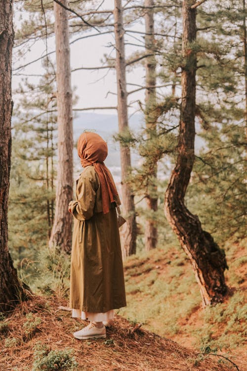 Woman standing in forest among evergreen trees