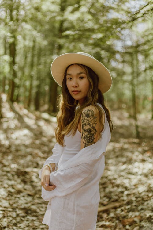 Tattooed Asian teen in hat in woods
