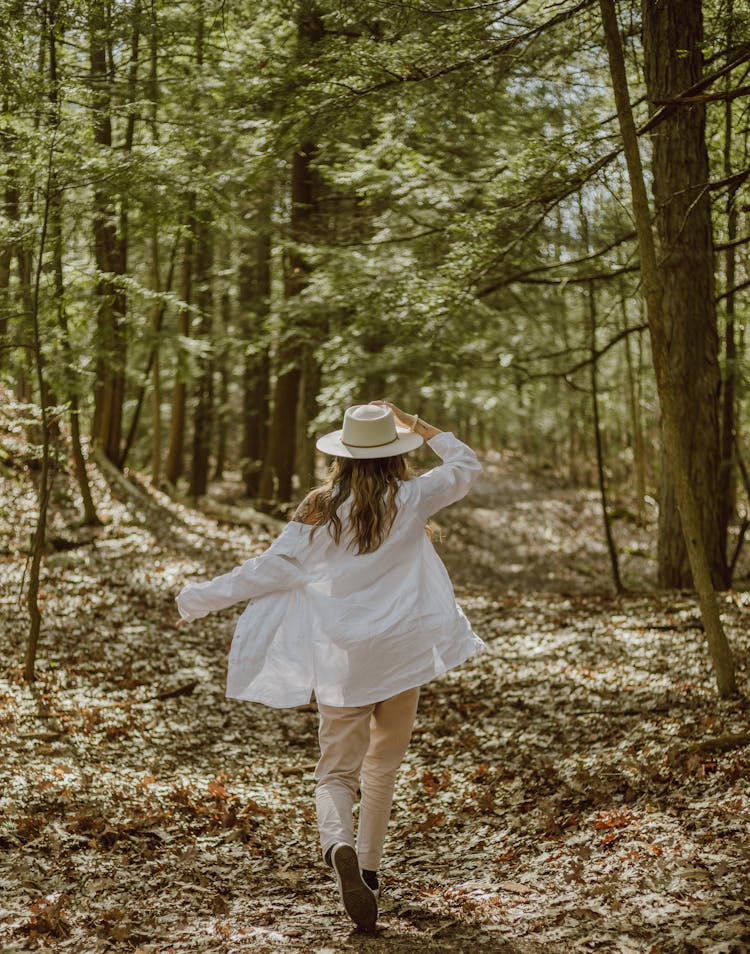 Unrecognizable Stylish Woman In Hat Walking On Path In Forest