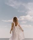 Unrecognizable tattooed woman admiring ocean under cloudy sky