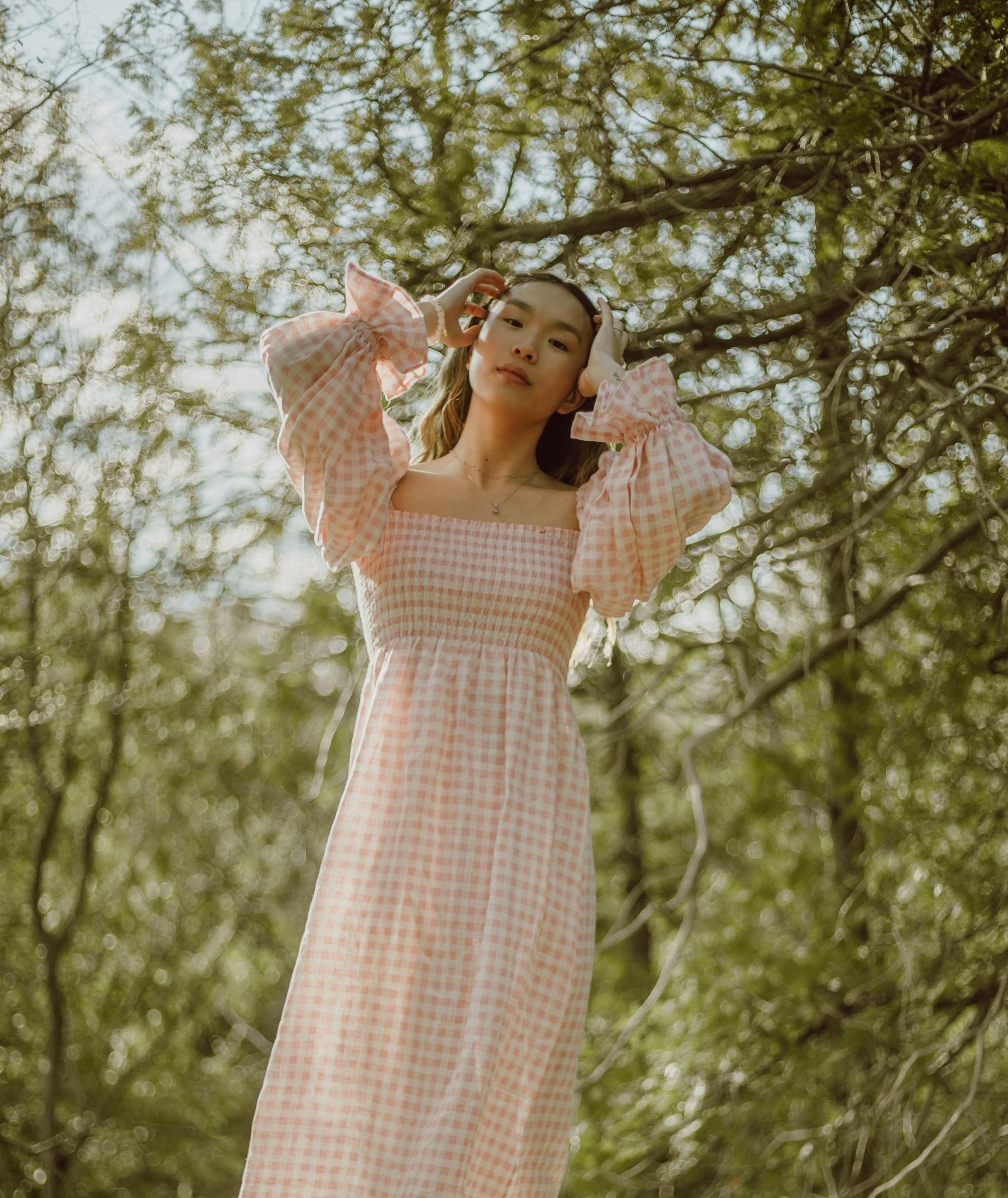 A woman in a dress in a forest, touching her hair