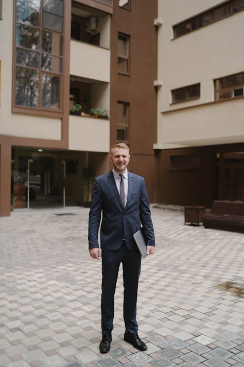 Man in Blue Suit Holding a Laptop