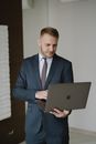 Man in Suit Using Laptop while Standing in the Room