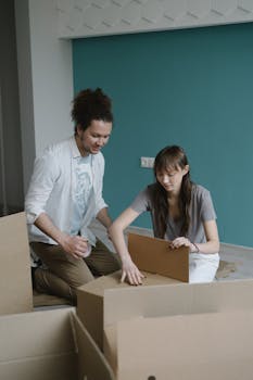 A young couple unpacking cardboard boxes in their new apartment, signifying a fresh start.