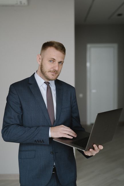 Young businessman in a suit using a laptop indoors, embodying corporate professionalism.