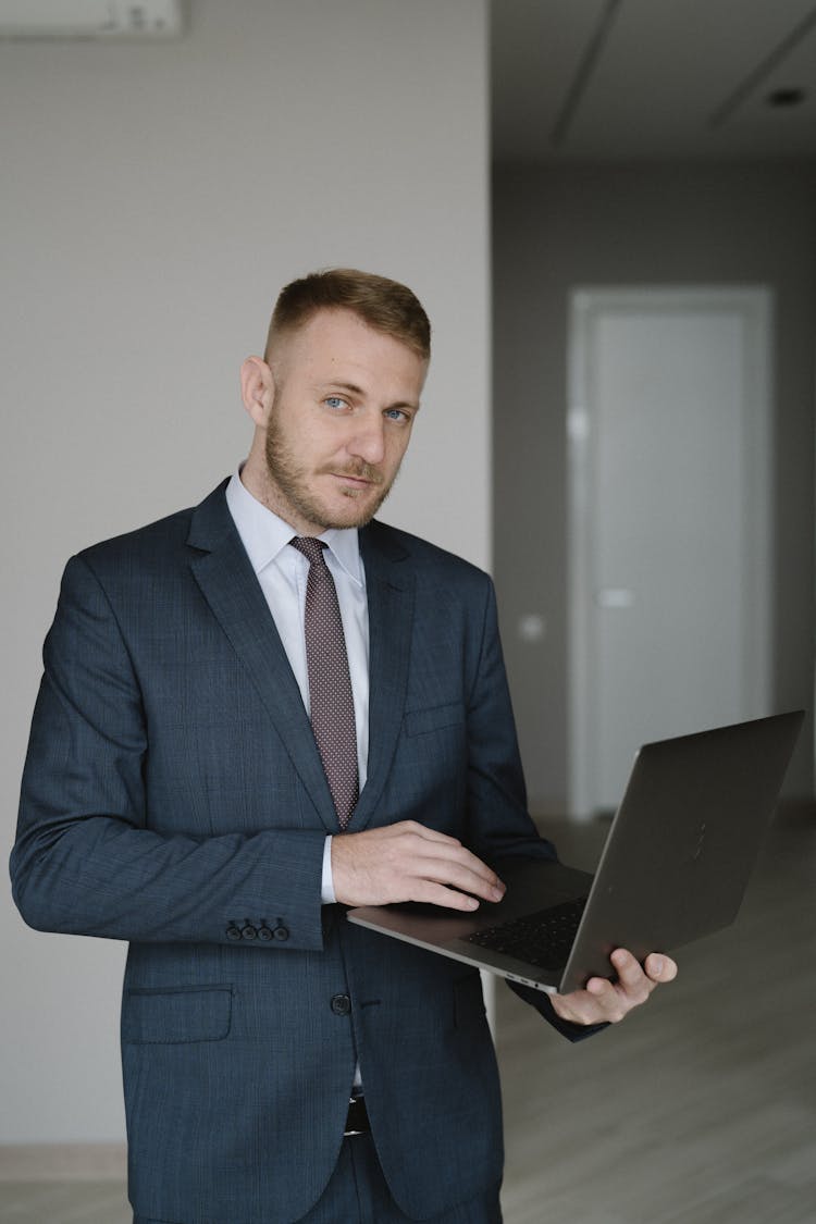 Man In Blue Suit Holding A Laptop