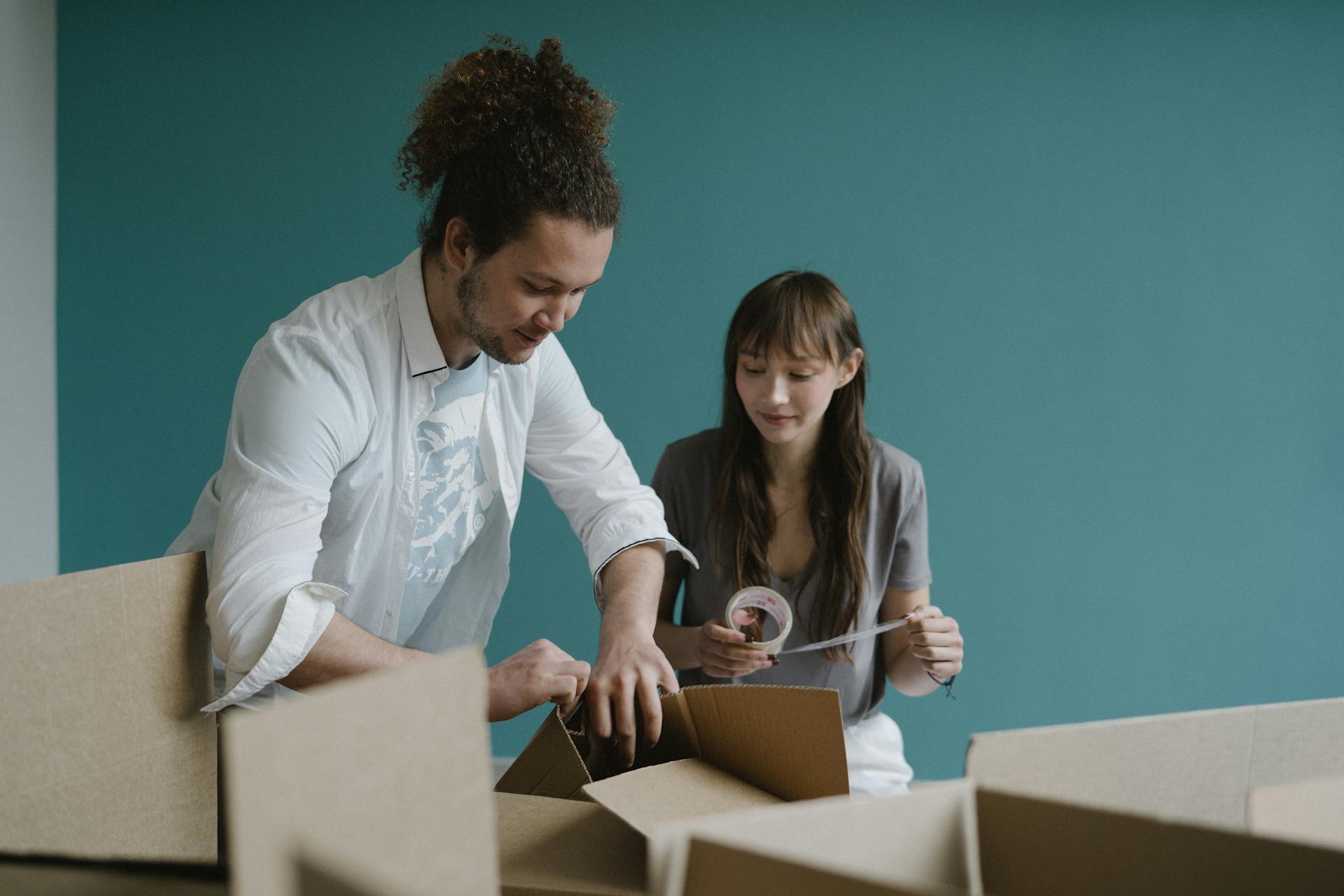 Young couple smiling while unpacking boxes in their new apartment. Moving in and home concept.