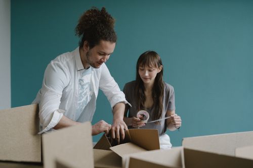 Free Young couple smiling while unpacking boxes in their new apartment. Moving in and home concept. Stock Photo