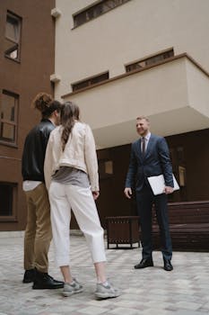 A professional realtor showing a new apartment to a young couple in a city setting.