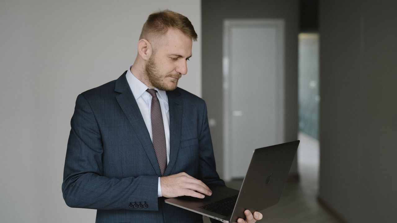 Businessman in suit works on laptop in a modern office setting, conveying professionalism.