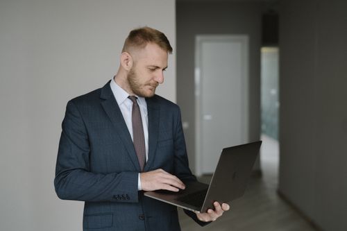 Free Businessman in suit works on laptop in a modern office setting, conveying professionalism. Stock Photo