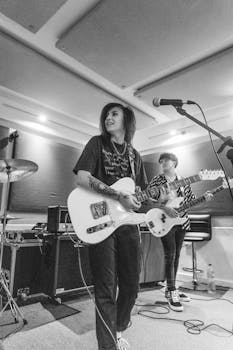 Black and white photo of female guitarist performing in a music studio.