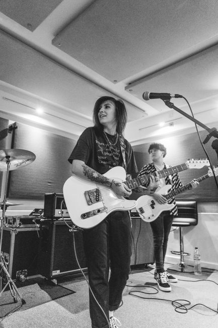 Black and white photo of female guitarist performing in a music studio.