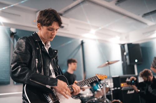 Photo of Man in Black Leather Jacket Playing Guitar