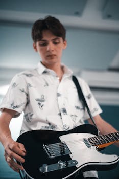 Young adult male playing an electric guitar in an indoor setting, showcasing musical talent.