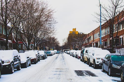 Met Sneeuw Bedekte Weg En Inline Geparkeerde Voertuigen Tussen Gebouwen Met 2 Verdiepingen Onder Witte Lucht