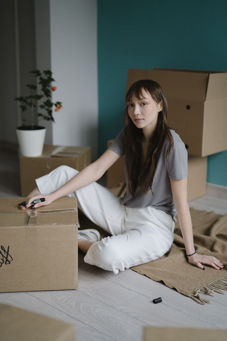 Spread illustration: a young woman sitting among cardboard boxes in her new flat — photo by Anastasia Shuraeva on Pexels