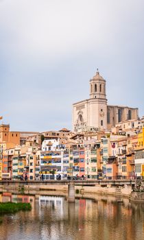 Scenic view of colorful riverside houses and iconic cathedral in Girona, España, reflecting in river.
