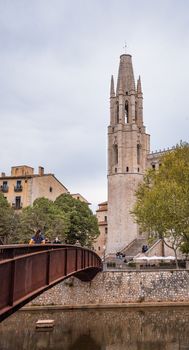 Stunning view of a historic church tower and a pedestrian bridge in Girona, Spain, offering a blend of history and architecture.