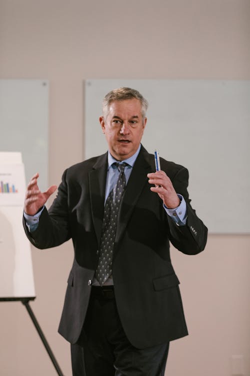Free A businessman in corporate attire delivering a presentation indoors. Stock Photo Free A businessman in corporate attire delivering a presentation indoors. Stock Photo